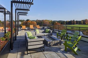a patio with couches and chairs and a fire pit on a roof